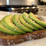 Close-up of avocado toast on whole grain bread in a white marble kitchen