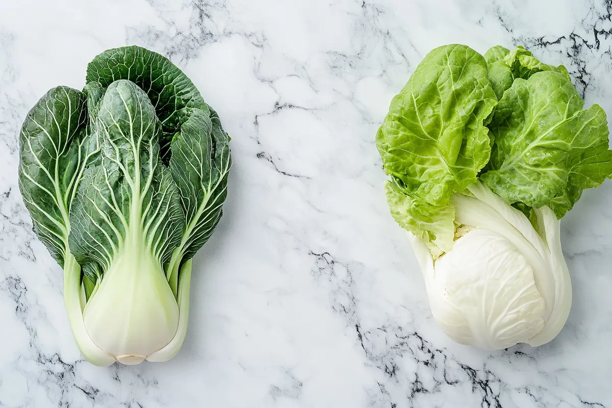 Napa cabbage and bok choy side by side on a white marble kitchen counter